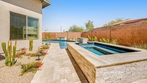 A modern outdoor pool area with a stone wall, a patio, and cacti. - Stylish home with pool & spa, ping-pong table, WiFi & fireplace - great location (Paradise Valley)