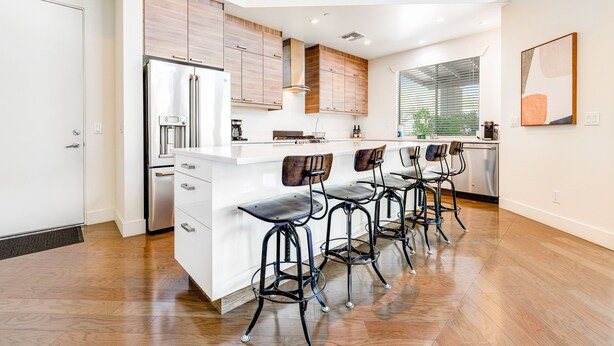 A modern kitchen with a central island, bar stools, wooden cabinets, and a stainless steel refrigerator. - Stylish home with pool & spa, ping-pong table, WiFi & fireplace - great location (Paradise Valley)