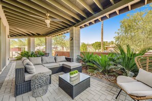 An outdoor patio area with a covered seating arrangement, a coffee table, and a variety of plants. - Stylish home with pool & spa, ping-pong table, WiFi & fireplace - great location (Paradise Valley)