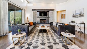 A modern living room with a fireplace, leather sofas, and a patterned rug. - Stylish home with pool & spa, ping-pong table, WiFi & fireplace - great location (Paradise Valley)