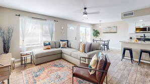 Ein modernes Wohnzimmer mit einer Eckcouch, einem Couchtisch und einem gemusterten Teppich.