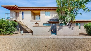 Ein zweistöckiges Haus mit einer Veranda, einer Treppe und einem kleinen Balkon.