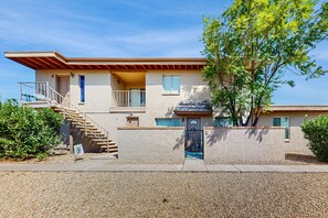 A two-story house with a covered porch, a staircase, and a small balcony. - Modern townhome with pool, AC, W/D, grill, and private patio (Fountain Hills)