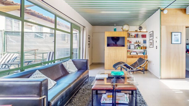 Una sala de estar moderna con un sofá de cuero, una mesa de centro de vidrio y una estantería.