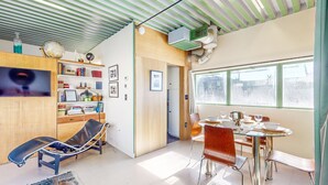 Una sala de estar moderna con una mesa de vidrio, sillones de cuero, un televisor y una estantería.