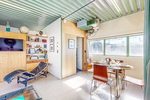 A modern living room with a glass table, leather chairs, a TV, and a bookshelf. - Historic flat in the heart of downtown with pool access and private terrace (Palm Springs)
