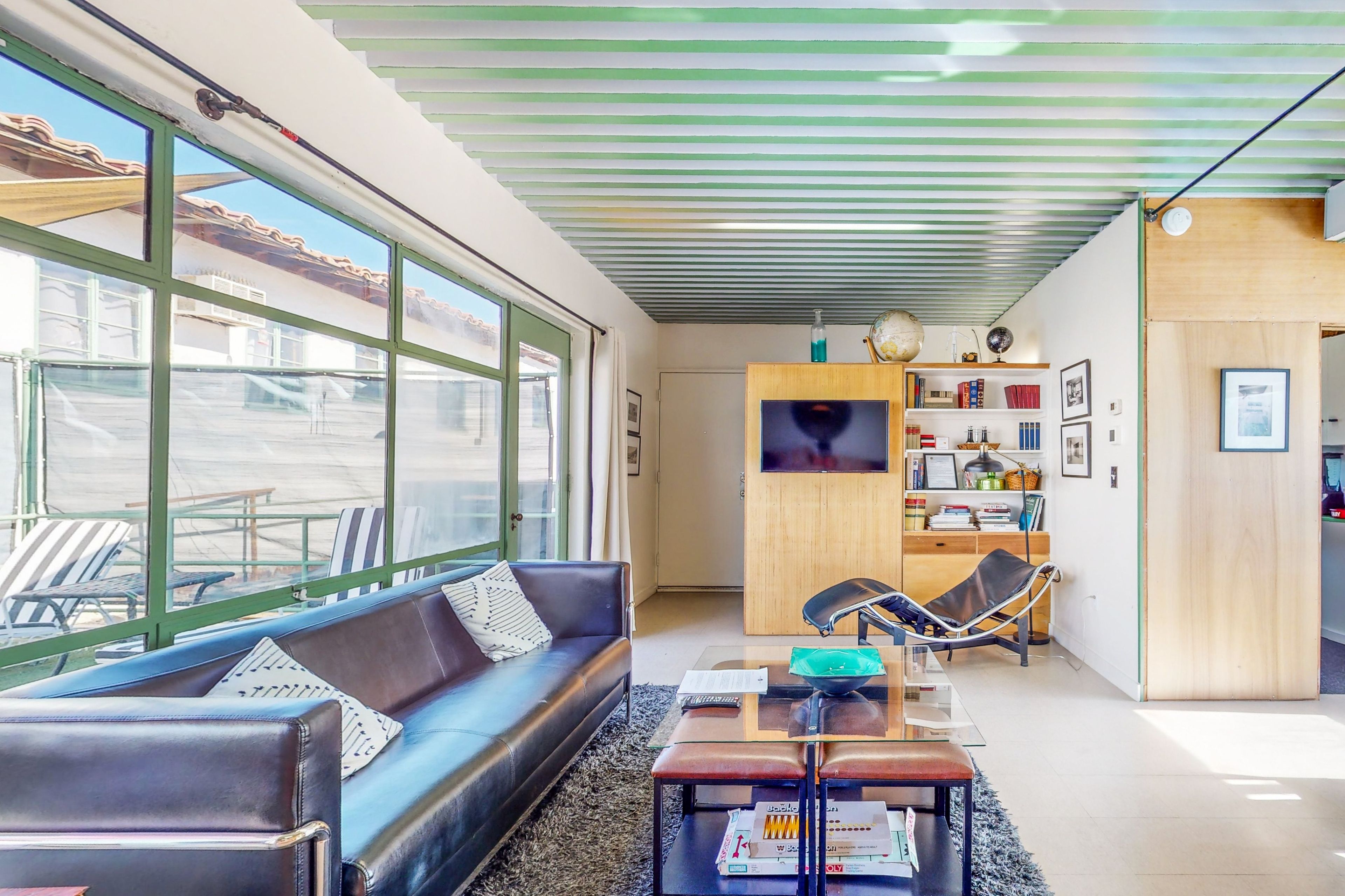 A modern living room with a leather sofa, a glass coffee table, and a television on a wooden cabinet.