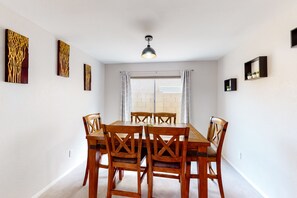Un coin repas avec une table et des chaises en bois, un luminaire suspendu et des œuvres d’art accrochées aux murs.
