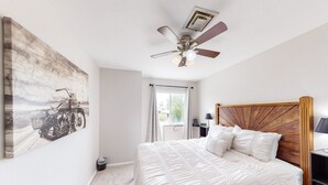 A bedroom with a bed, a ceiling fan, a window with curtains, and a wall-mounted artwork. - Retro home with enclosed yard, covered patio, grill, firepit, AC, & washer/dryer (Glendale)