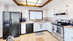 A modern kitchen with white cabinets, a black refrigerator, a dishwasher, a stove, and a window with blinds. - Retro home with enclosed yard, covered patio, grill, firepit, AC, & washer/dryer (Glendale)