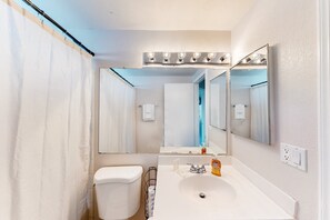 Un baño con un lavabo blanco, un espejo y una cortina de ducha.