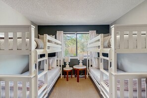 A room with bunk beds, a small table, and a window with curtains. - Spacious home w/ large yard, deck, mountain view, fire pit & grill (Flagstaff)