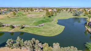 Ein Golfplatz mit Teich, umgeben von Bäumen und Gebäuden.