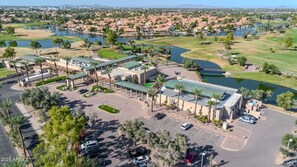 An aerial view of a golf resort with multiple buildings, parking areas, and surrounding landscapes including water bodies and greenery. - Townhouse with central AC, patio, grill, washer/dryer, pool & hot tub access (Chandler)