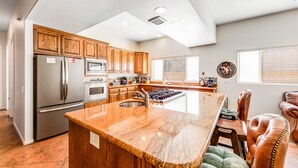 A modern kitchen with wooden cabinets, stainless steel appliances, and a large granite island. - Mountain-view home with private pool & spa, near trails - 3BR #220080 (La Quinta)