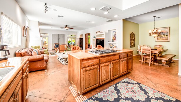 A spacious living area with a large wooden island, a kitchen with a built-in stove, and a dining area with a wooden table and chairs. - Mountain-view home with private pool & spa, near trails - 3BR #220080 (La Quinta)