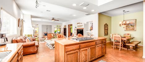 A spacious living area with a large wooden island, a kitchen with a built-in stove, and a dining area with a wooden table and chairs.