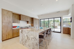 A modern kitchen with a large island, wooden cabinets, and a view to the outside. - Stunning Modern Home w/Mountain Views + Private Pool, Spa & Grill  - Dog ok (Rancho Mirage)