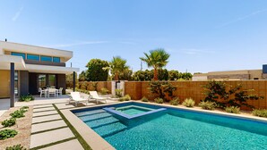 Et moderne hus med swimmingpool, havemøbler og en patio.