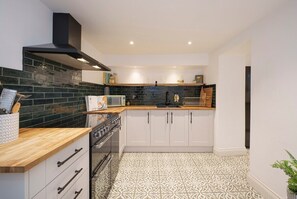 A modern kitchen with white cabinets, a wooden countertop, and a patterned floor. - Stunning, Spacious Bath Townhouse w/parking (Bath)