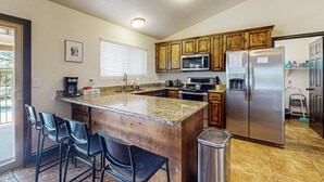 A kitchen with granite countertops, wooden cabinets, stainless steel appliances, and a trash can. - Charming & sunlit villa with private pool, patio, & firepit - near golf & trails (Mesa)