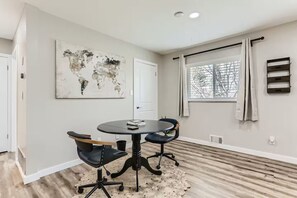 Una habitación moderna con una mesa redonda, dos sillas, un cuadro con un mapa del mundo, una ventana con cortinas y un radiador.