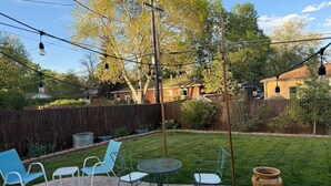 Eine Terrasse mit Stühlen und Tisch, umgeben von einem Holzzaun und Bäumen.