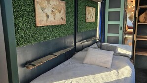 A modern bedroom with a bed, green wall, world map artwork, and a ceiling fan. - Cozy-Chic Container Tiny Home + Treehouse Deck (Wagoner)