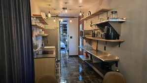 A modern kitchen with stainless steel appliances, a tiled floor, and pendant lighting. - Cozy-Chic Container Tiny Home + Treehouse Deck (Wagoner)