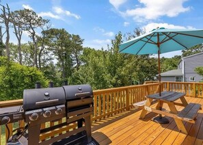 A wooden deck with a grill, picnic table, and umbrella. - 3-bedroom house in lovely Sandbridge Beach-Budget Getaway (Virginia Beach)