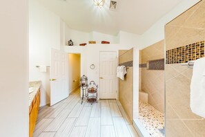 A modern bathroom with a shower, tiled walls, and a wooden floor.