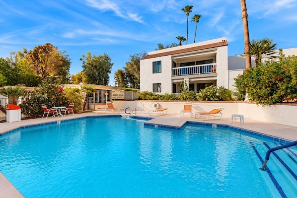 A swimming pool with lounge chairs and a building with a balcony in the background. - Mtn-view 2nd-floor renovated condo near trails with 4 pools, pool spas, balcony (Palm Springs)