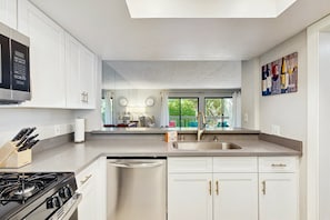 A modern kitchen with white cabinetry, a stainless steel dishwasher, and a gas stove. - Mtn-view 2nd-floor renovated condo near trails with 4 pools, pool spas, balcony (Palm Springs)