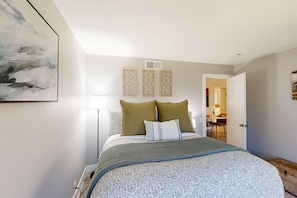 A bedroom with a bed, a painting, a lamp, and a door leading to a dining area. - Mtn-view 2nd-floor renovated condo near trails with 4 pools, pool spas, balcony (Palm Springs)
