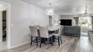 A modern dining area with a rectangular table and six chairs, a ceiling fan, and a large window with curtains. - Group Getaway Near Eufaula Lake & Boat Ramp! (Eufaula)