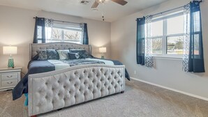 A bedroom with a tufted headboard bed, two bedside tables, a ceiling fan, and a large window with curtains. - Group Getaway Near Eufaula Lake & Boat Ramp! (Eufaula)