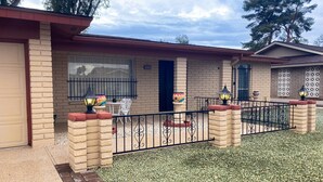 A residential property with a brick facade, a gated entrance, and outdoor seating area with a table and chairs. - Snowbird-friendly golf-front home with pool, hot tub, grill, smart TVs, W/D, AC (Mesa)
