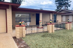 A residential property with a brick facade, a gated entrance, and outdoor seating area with a table and chairs. - Snowbird-friendly golf-front home with pool, hot tub, grill, smart TVs, W/D, AC (Mesa)