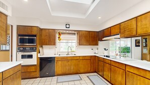 A modern kitchen with wooden cabinets, a built-in oven, microwave, and dishwasher. - Snowbird-friendly golf-front home with pool, hot tub, grill, smart TVs, W/D, AC (Mesa)
