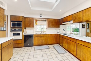 A modern kitchen with wooden cabinets, a built-in oven, microwave, and dishwasher. - Snowbird-friendly golf-front home with pool, hot tub, grill, smart TVs, W/D, AC (Mesa)