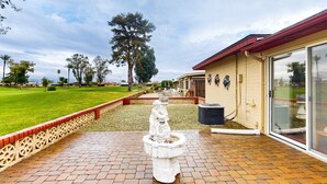 A courtyard with a central fountain, a brick pathway, and a building with a glass door. - Snowbird-friendly golf-front home with pool, hot tub, grill, smart TVs, W/D, AC (Mesa)