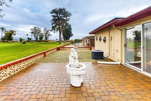 A courtyard with a central fountain, a brick pathway, and a building with a glass door. - Snowbird-friendly golf-front home with pool, hot tub, grill, smart TVs, W/D, AC (Mesa)