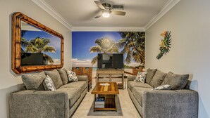 A living room with two grey sofas, a wooden coffee table, a flat-screen TV, and a ceiling fan. - Luxury Waterfront Living! Naples Resort Condo (Naples)