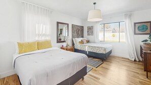A modern bedroom with a large bed, a smaller bed, a nightstand, a dresser, and a window with curtains. - Sunny downtown home with private pool, hammock, enclosed backyard, grill, patio (Phoenix)