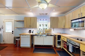 A compact kitchen with a dishwasher, stove, and microwave. There is a window with a view of plants outside. - Cozy woodland with fireplace & patio, near trails, Flagstaff & national forest (Flagstaff)