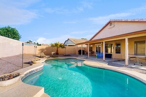 A swimming pool with a tiled edge, a covered patio area with seating, and a building with a tiled roof. - Modern home w/ private heated pool, backyard w/ patio & BBQ grill (Mesa)