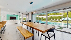 A modern indoor space with a large wooden table, seating, and a view of an outdoor swimming pool. - Poolside Paradise in the Desert – Your Perfect Palm Springs Escape Awaits. (Palm Springs)
