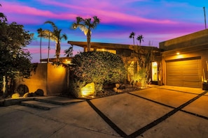 Una casa moderna con un camino bien iluminado, palmeras y un cartel que dice 'Villa Calefón Del Sol'.