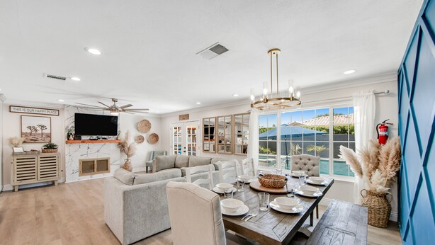 A spacious living area with a large sofa, dining table set for four, and a view of the outdoors. - Designer dream with fireplace, game room, private pool, outdoor kitchen, firepit (Palm Springs)