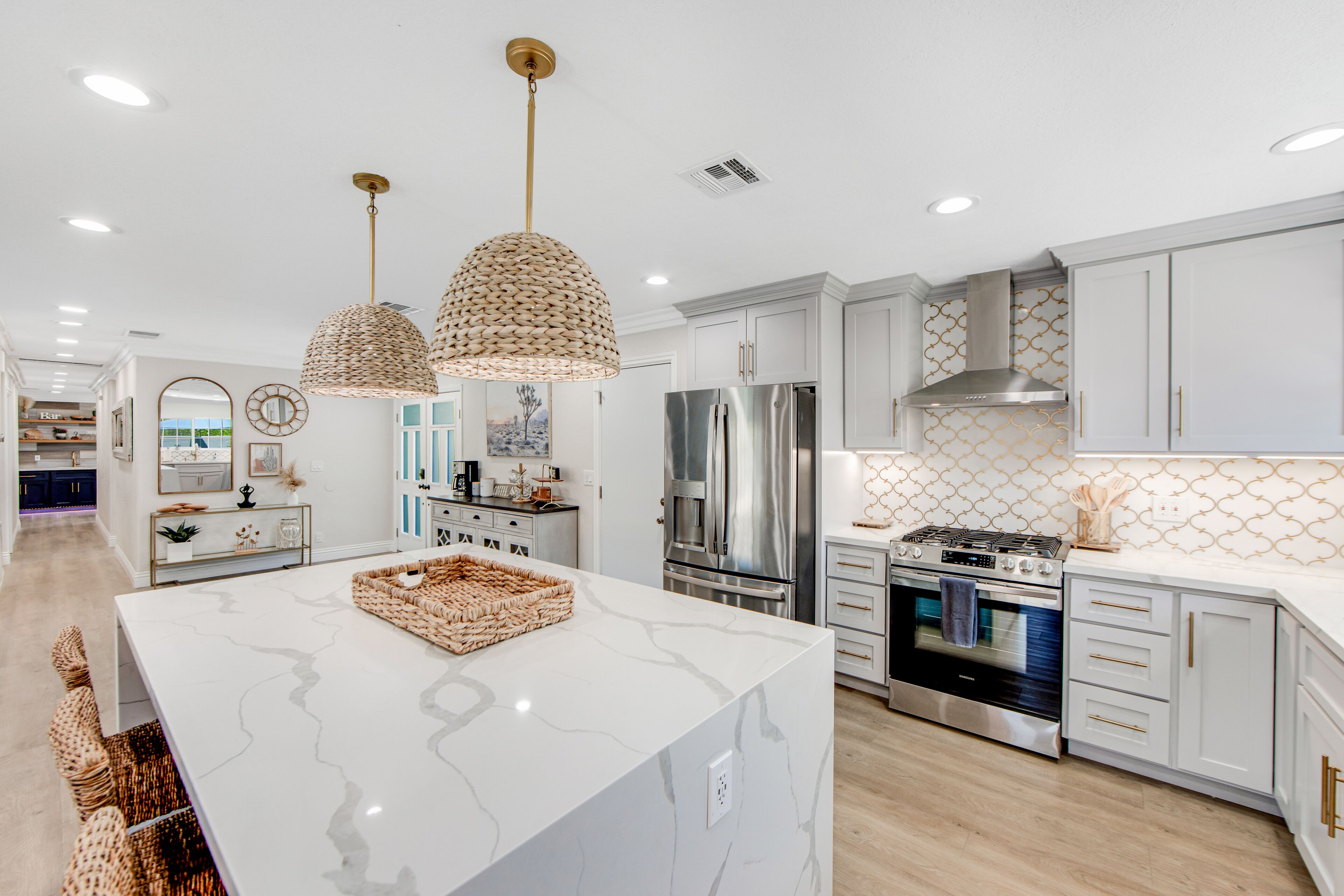 A modern kitchen with white cabinetry, stainless steel appliances, and a marble island.